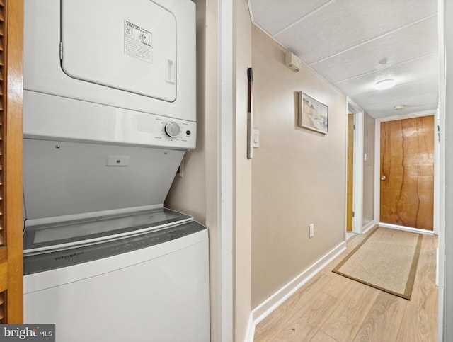 clothes washing area with stacked washing maching and dryer and light wood-type flooring