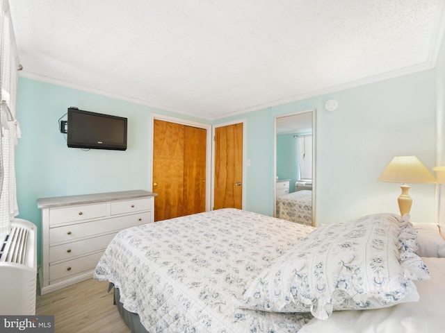 bedroom with ornamental molding and light hardwood / wood-style floors