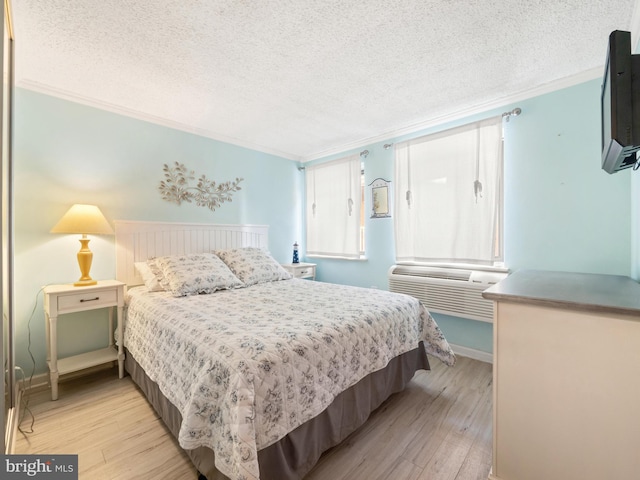 bedroom featuring light hardwood / wood-style floors, crown molding, and a textured ceiling