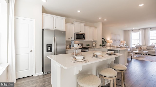 kitchen featuring a kitchen breakfast bar, stainless steel appliances, sink, light hardwood / wood-style flooring, and white cabinetry