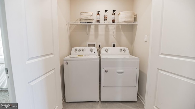 laundry area with washer and clothes dryer and light tile patterned floors