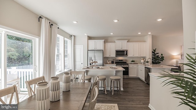 kitchen featuring a kitchen breakfast bar, stainless steel appliances, dark wood-type flooring, sink, and white cabinetry