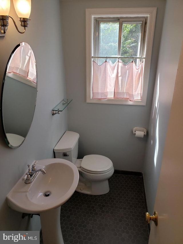 bathroom with toilet, tile patterned flooring, and sink