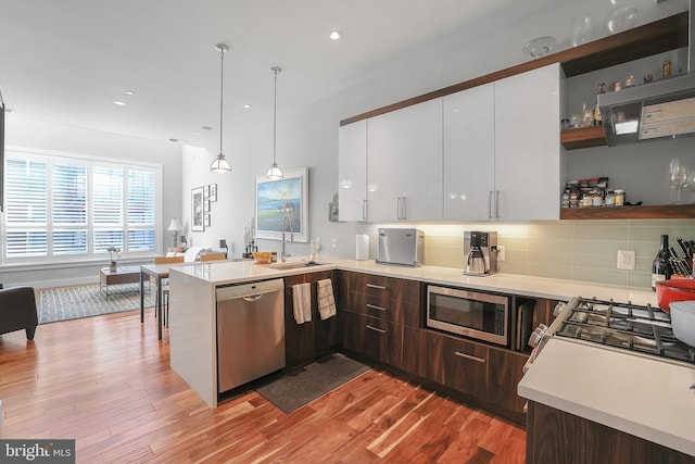 kitchen featuring dark brown cabinetry, stainless steel appliances, hanging light fixtures, and white cabinets