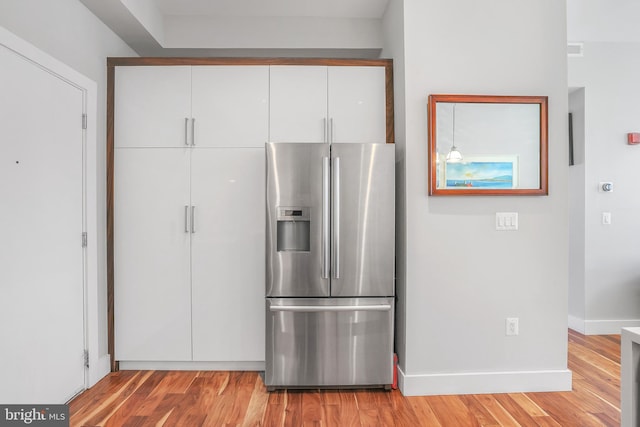 kitchen with white cabinetry, stainless steel fridge, and light hardwood / wood-style floors