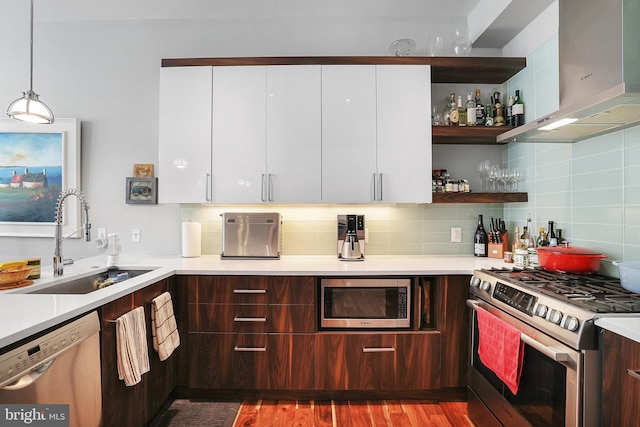 kitchen featuring appliances with stainless steel finishes, pendant lighting, white cabinetry, sink, and backsplash