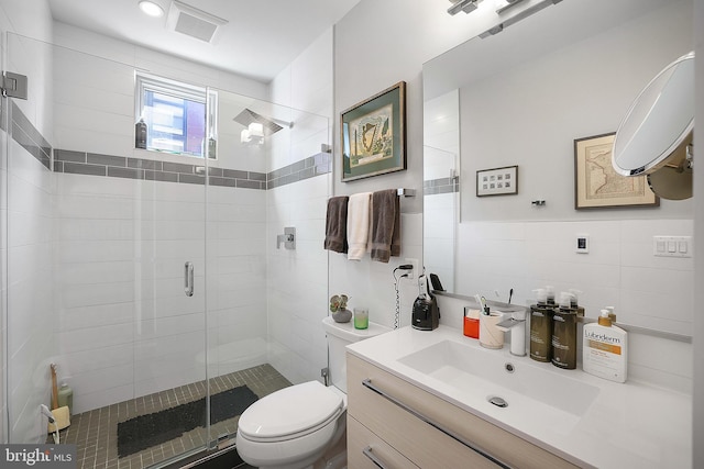 bathroom featuring vanity, toilet, an enclosed shower, and tile walls