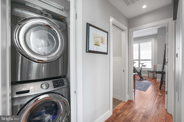 laundry area with dark wood-type flooring and stacked washing maching and dryer