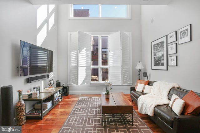 living room featuring hardwood / wood-style flooring and a towering ceiling