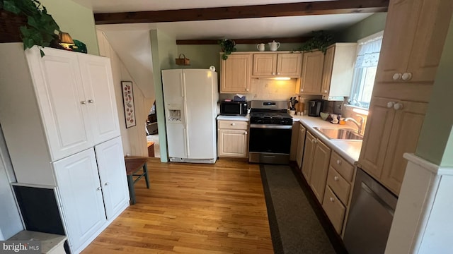 kitchen featuring stainless steel gas range, sink, light wood-type flooring, beam ceiling, and white refrigerator with ice dispenser