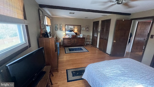 bedroom with beamed ceiling, light hardwood / wood-style floors, and ceiling fan