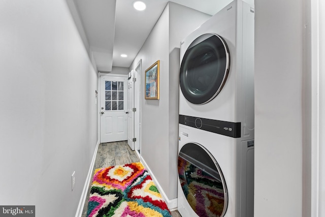 laundry room with light hardwood / wood-style floors and stacked washing maching and dryer