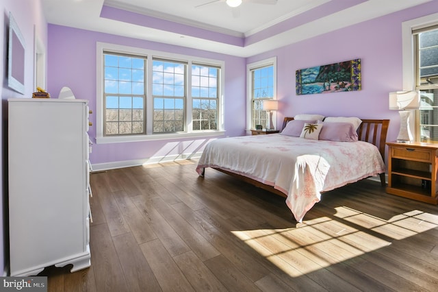 bedroom with crown molding, baseboards, a raised ceiling, and hardwood / wood-style floors