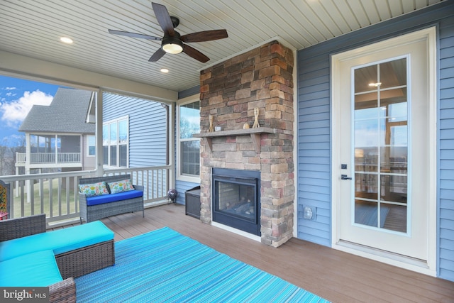 unfurnished sunroom featuring ceiling fan, an outdoor stone fireplace, and wooden ceiling