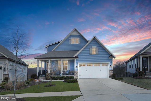 view of front of property featuring a garage, concrete driveway, stone siding, a porch, and a front yard