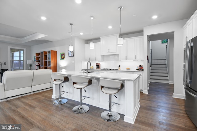 kitchen with dark wood-style flooring, a sink, white cabinets, freestanding refrigerator, and stainless steel gas stovetop