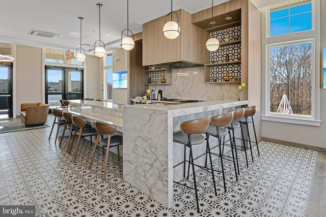 kitchen featuring a wealth of natural light, modern cabinets, a breakfast bar area, and backsplash