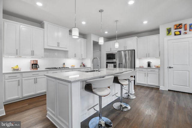 kitchen with appliances with stainless steel finishes, dark wood-style flooring, a sink, and white cabinets