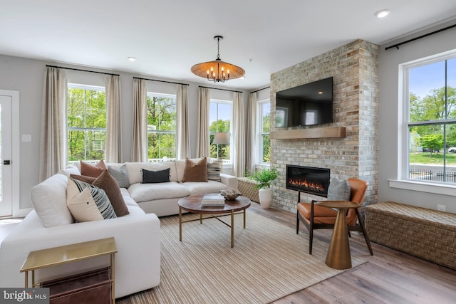 living room with a fireplace, a chandelier, and light wood-type flooring