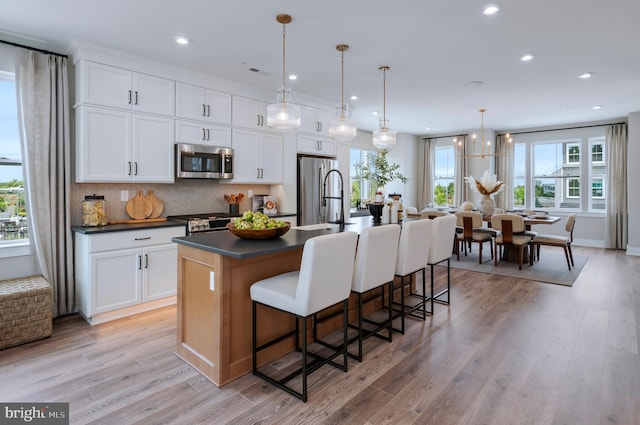 kitchen with white cabinetry, appliances with stainless steel finishes, and a center island with sink