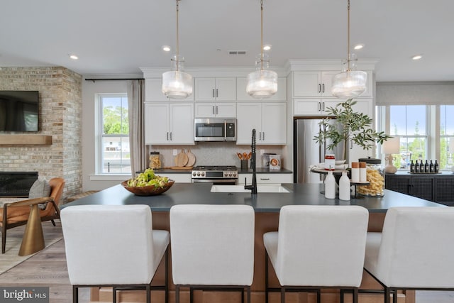 kitchen featuring stainless steel appliances, white cabinetry, and an island with sink