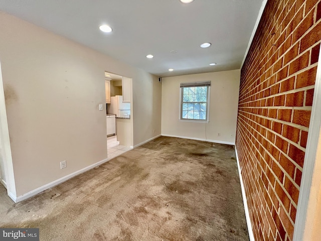 unfurnished room with brick wall and light carpet