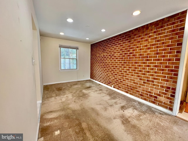 carpeted empty room featuring brick wall