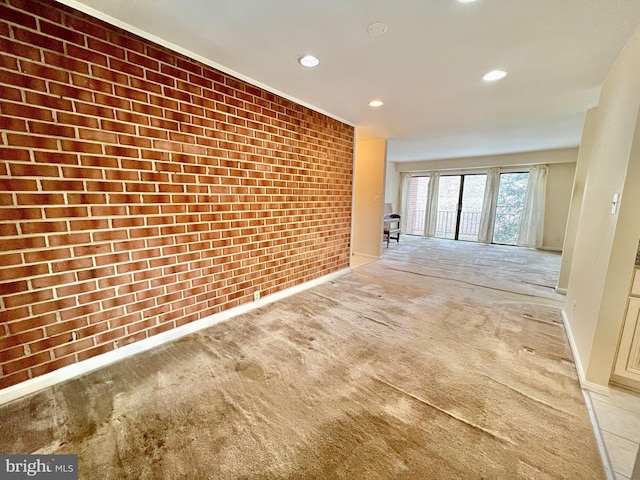 interior space featuring light colored carpet and brick wall