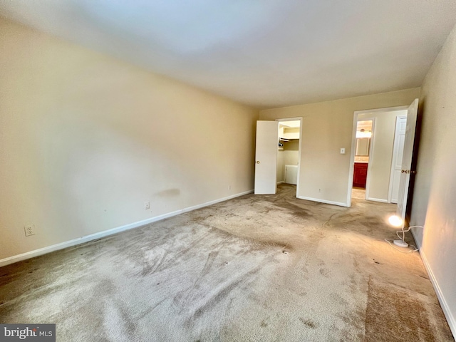 unfurnished bedroom with a spacious closet, light colored carpet, and a closet