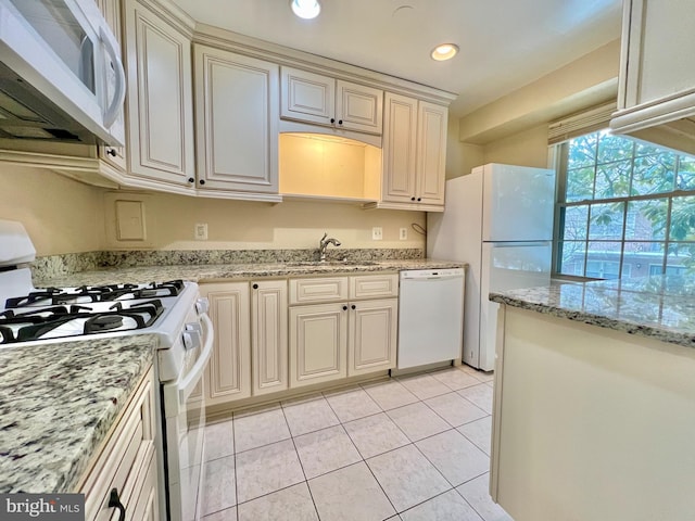 kitchen with light stone countertops, white appliances, sink, light tile patterned floors, and cream cabinetry