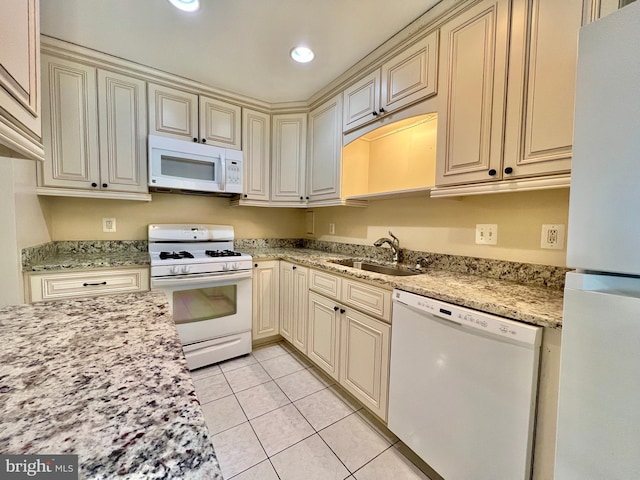 kitchen with light tile patterned floors, sink, white appliances, and cream cabinets