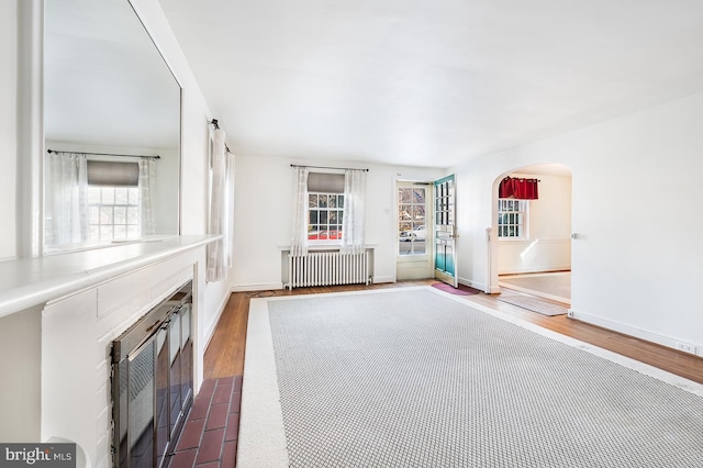 unfurnished living room featuring radiator and hardwood / wood-style floors