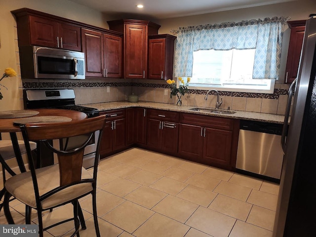 kitchen with sink, light stone counters, decorative backsplash, light tile patterned floors, and appliances with stainless steel finishes