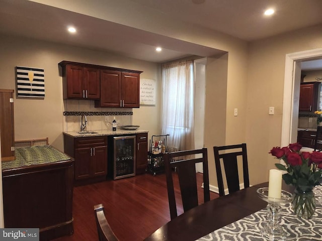 kitchen featuring dark wood-type flooring, sink, wine cooler, decorative backsplash, and light stone counters