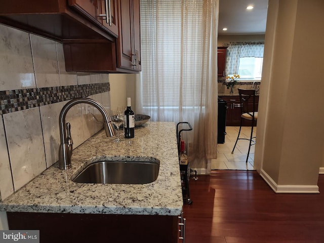 kitchen featuring dark hardwood / wood-style flooring, light stone counters, and sink