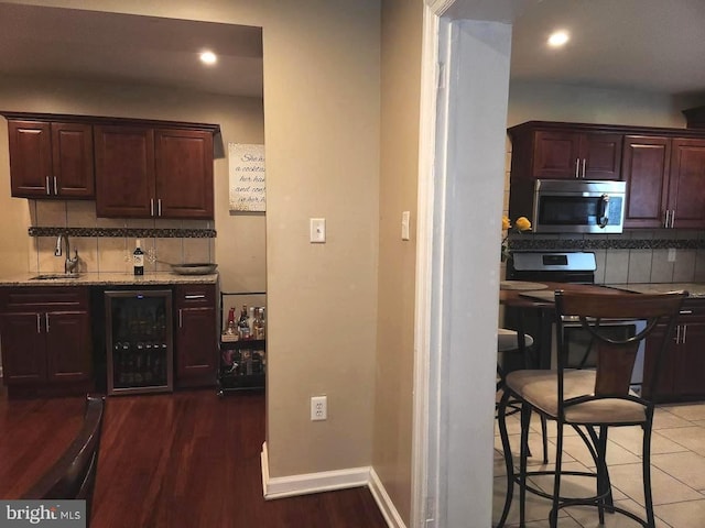 kitchen with dark brown cabinetry, sink, dark wood-type flooring, wine cooler, and backsplash