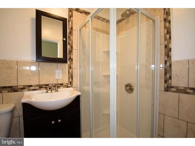 bathroom with tile walls, vanity, an enclosed shower, and toilet