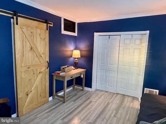 bedroom featuring a barn door, hardwood / wood-style flooring, a closet, and ornamental molding