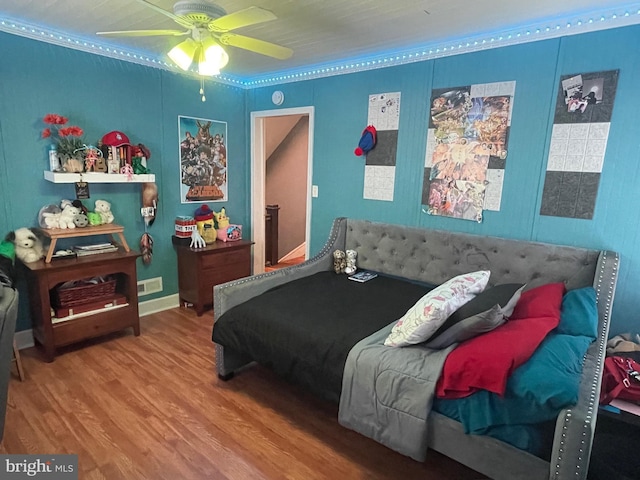 bedroom with hardwood / wood-style floors, ceiling fan, and crown molding