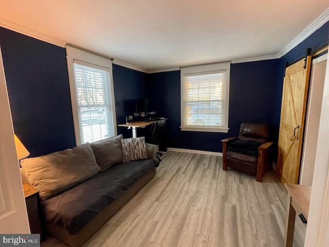 living room with a barn door, ornamental molding, a healthy amount of sunlight, and light wood-type flooring