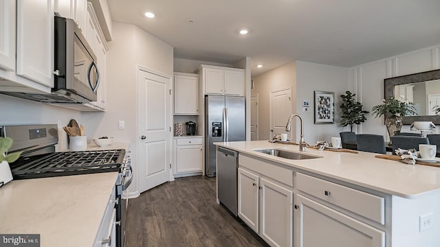 kitchen featuring white cabinets, a center island with sink, sink, appliances with stainless steel finishes, and dark hardwood / wood-style flooring