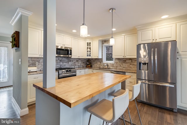 kitchen featuring a kitchen breakfast bar, appliances with stainless steel finishes, white cabinets, and wood counters