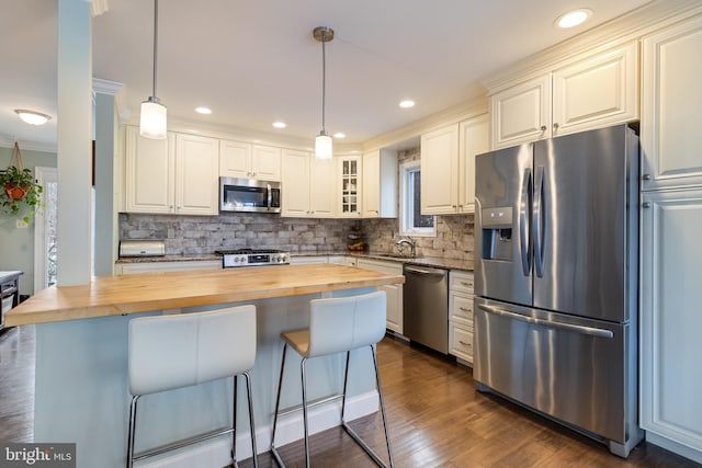 kitchen with a breakfast bar, wooden counters, a center island, hanging light fixtures, and stainless steel appliances