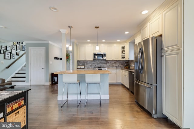 kitchen with butcher block countertops, white cabinetry, a breakfast bar area, hanging light fixtures, and stainless steel appliances