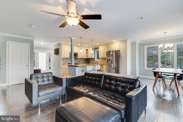 living room featuring crown molding, plenty of natural light, ceiling fan with notable chandelier, and hardwood / wood-style flooring