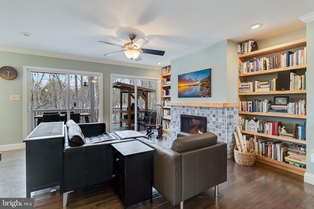 living room with ornamental molding, dark hardwood / wood-style floors, ceiling fan, and a fireplace