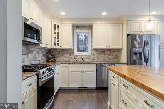 kitchen featuring pendant lighting, wood counters, sink, dark hardwood / wood-style flooring, and stainless steel appliances