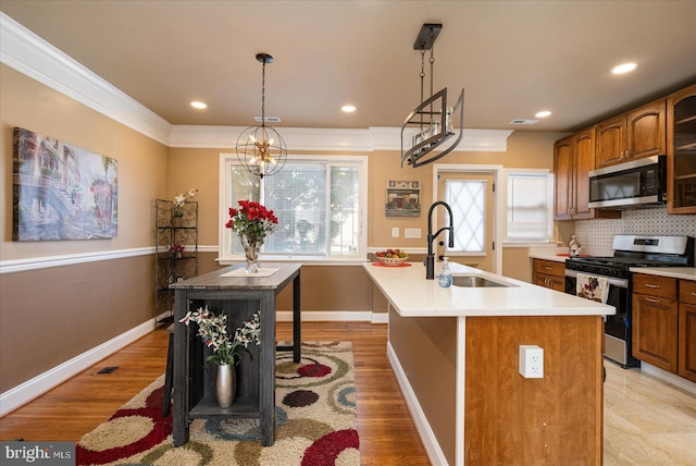 kitchen featuring an island with sink, appliances with stainless steel finishes, a kitchen breakfast bar, and decorative light fixtures