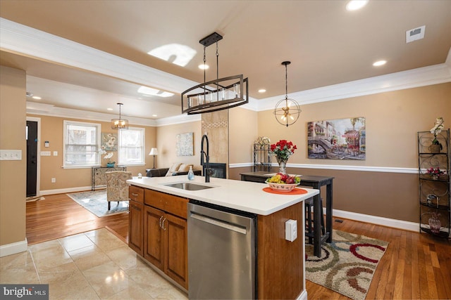 kitchen with sink, crown molding, decorative light fixtures, dishwasher, and an island with sink