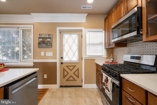 kitchen with decorative backsplash, ornamental molding, and stainless steel appliances